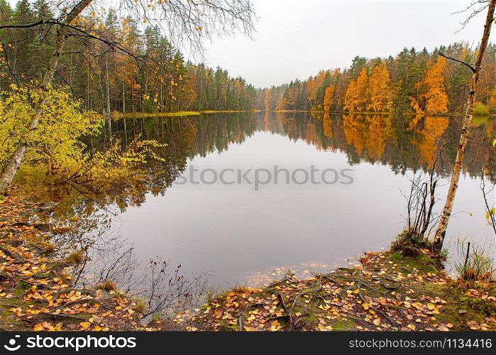 Colorful autumn landscape in Finland with reflection in water of lake