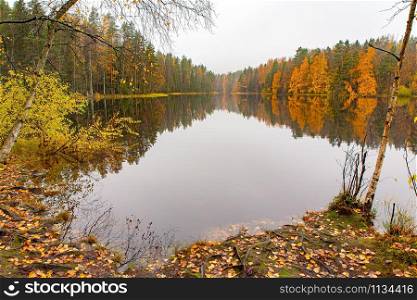 Colorful autumn landscape in Finland with reflection in water of lake