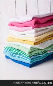 Colorful baby clothes of folded pile on a white background. Folded baby clothes