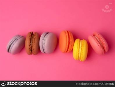 colorful baked macarons almond flour on a pink background, copy space, flat lay