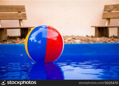 Colorful beach ball floating in pool.