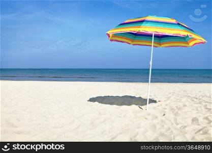 Colorful beach umbrella on the sandy beach on summer day. Blue sky and sea in the background