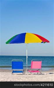 Colorful Beach Umbrella with Pink and Blue Deckchairs