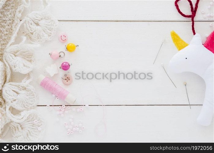colorful beads spool needle rag unicorn white wooden desk. High resolution photo. colorful beads spool needle rag unicorn white wooden desk. High quality photo