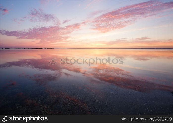 Colorful beautiful cloudy sunset over ocean water surface
