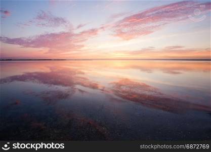 Colorful beautiful cloudy sunset over ocean water surface
