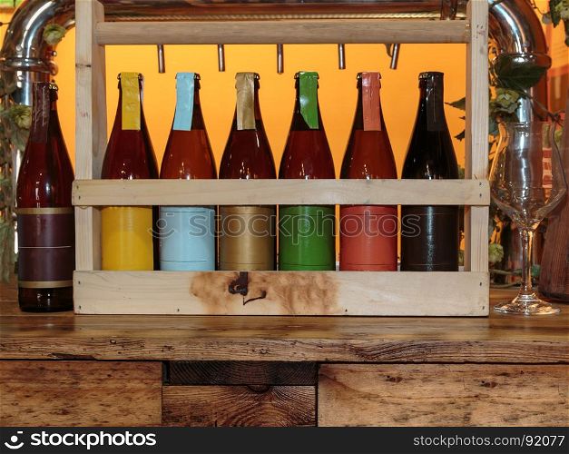 Colorful Beer Bottles on Wooden Table and Orange Background