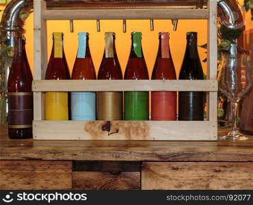 Colorful Beer Bottles on Wooden Table and Orange Background