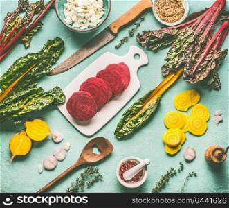 Colorful beetroot cooking flat lay. Red and yellow beetroot with chard leaves and ingredients on blue kitchen table background, top view. Vegan or vegetarian clean food concept