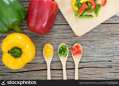 Colorful bell peppers and kitchen utensil on white wooden table. Top view