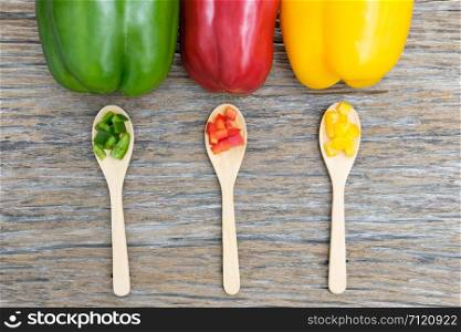 Colorful bell peppers and kitchen utensil on wooden table. Top view