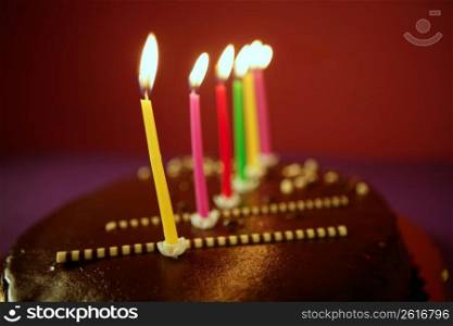Colorful birthday light candles in a chocolate cake red background