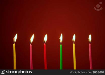Colorful birthday light candles in a row red background