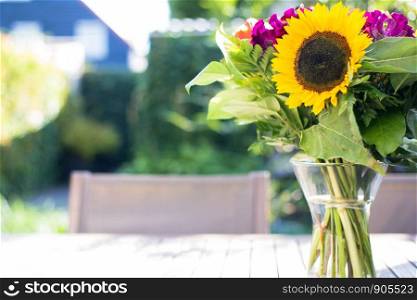 Colorful bright sunflower in vase in a green summer garden on wooden table. Selective focus. colorful. Colorful bright sunflower in vase in a green summer garden on wooden table. Selective focus.