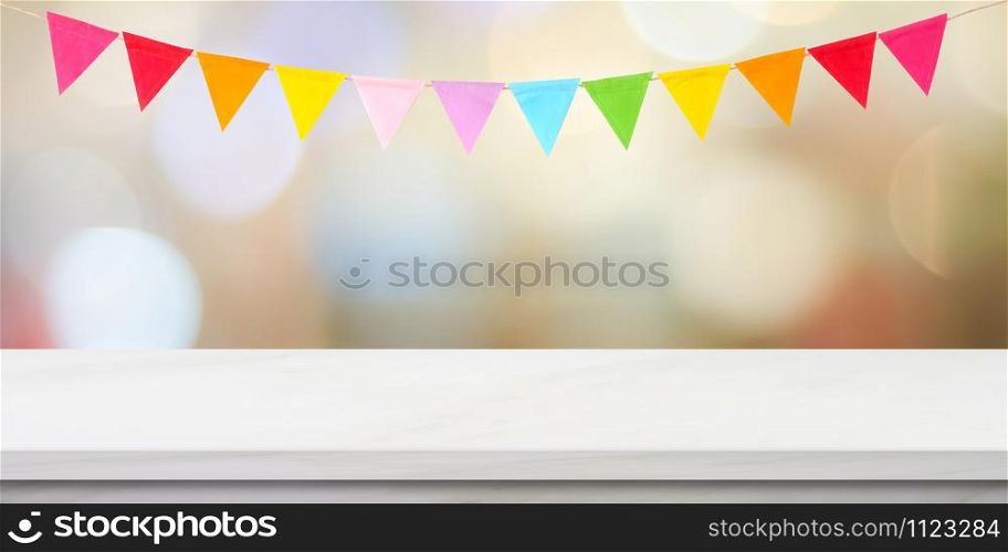 Colorful bunting party flags hanging on blur abstract bokeh light and white marble table background, birthday, anniversary, celebrate event, festival greeting card background, banner, backgdrop, mock up, template, wallpaper