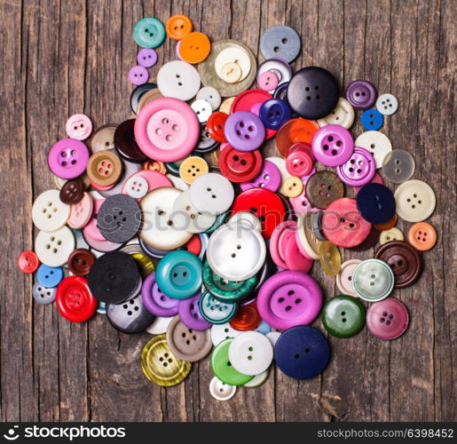 Colorful buttons heap on a wooden background. Colorful buttons heap