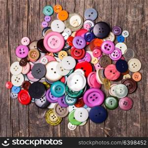 Colorful buttons heap on a wooden background. Colorful buttons heap