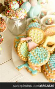 Colorful cake pops and cookies on white wooden desk
