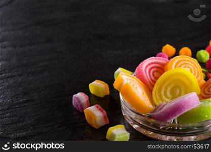 Colorful candies, jelly and marmalade and jellybeans around a central copy space on slate on background. Top view with copy space.