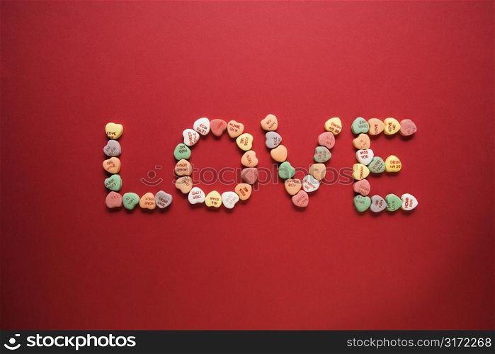Colorful candy hearts with sayings on them arranged to spell the word love.