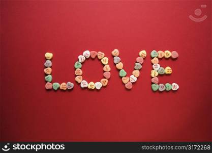 Colorful candy hearts with sayings on them arranged to spell the word love.
