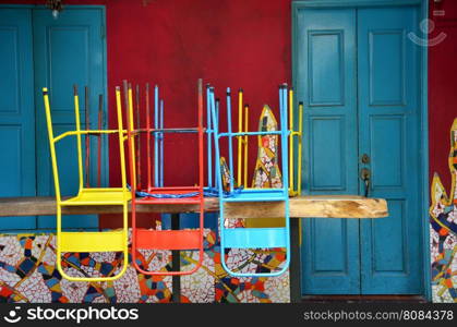 Colorful chairs on a wooden table in front of old shop, Singapore