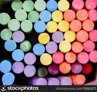 Colorful chalk in box for drawing on chalkboard on top view