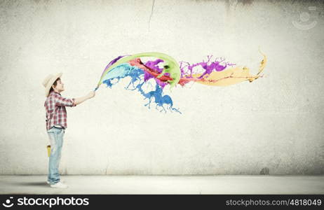 Colorful childhood. Boy of school age painting wall with brush