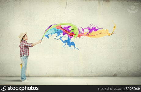 Colorful childhood. Boy of school age painting wall with brush