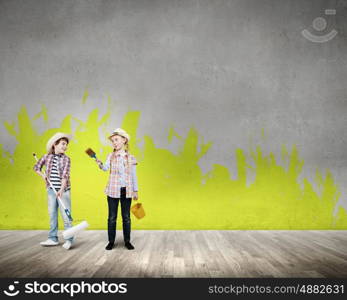 Colorful childhood. Two children of school age painting wall with roller