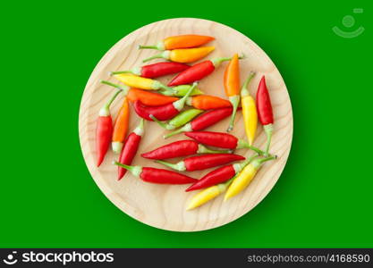 colorful chili peppers plate isolated on green background