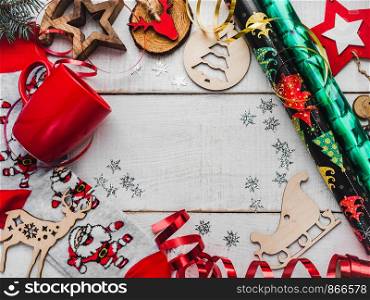 Colorful Christmas and New Year decorations and toys, warm socks with Santa, red mug on a white wooden surface. Place for your inscriptions. Top view, flat lay. Greeting card. Colorful, multicolored Christmas and New Year decorations