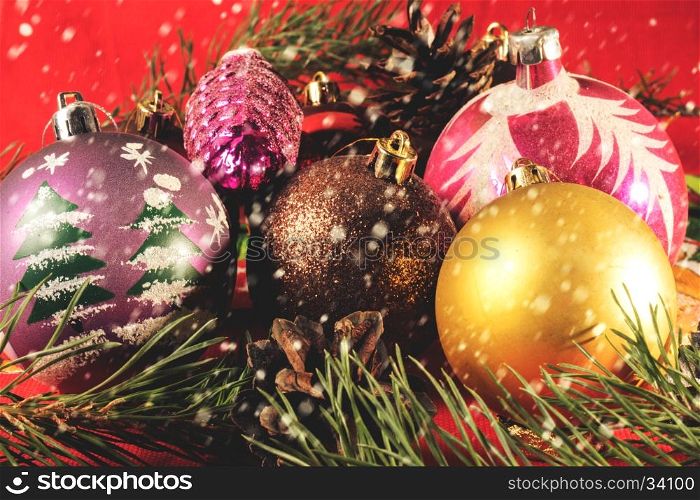 Colorful Christmas balls. Blurred background. falling snowflakes. Christmas balls lying on spruce branches. Blurred background and falling snowflakes