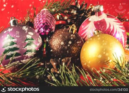 Colorful Christmas balls. Blurred background. falling snowflakes. Christmas balls lying on spruce branches. Blurred background and falling snowflakes