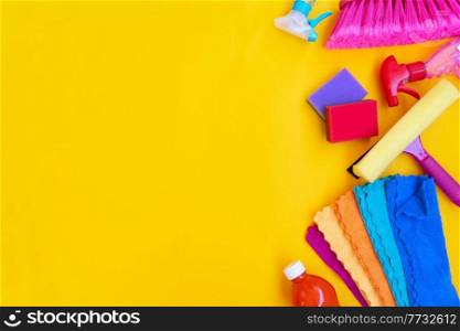 colorful cleaning supplies tools on illuminating yellow background, border with copy space, spring clean concept. cleaning supplies tools on plain background