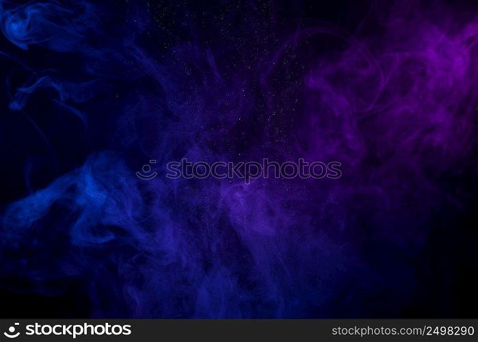 Colorful clouds of smoke and shiny dust on dark background