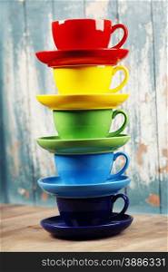 Colorful coffee cups on wooden table over blue background