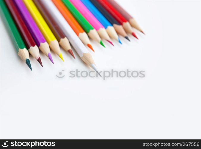 Colorful crayon pencils on white desktop with selected focus on the white color tips with copy space. Top view, closeup.