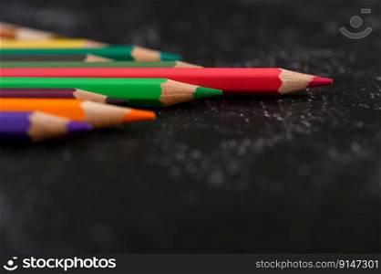 colorful crayon pencils with triangle shape on black background with copy space. Selective focus.