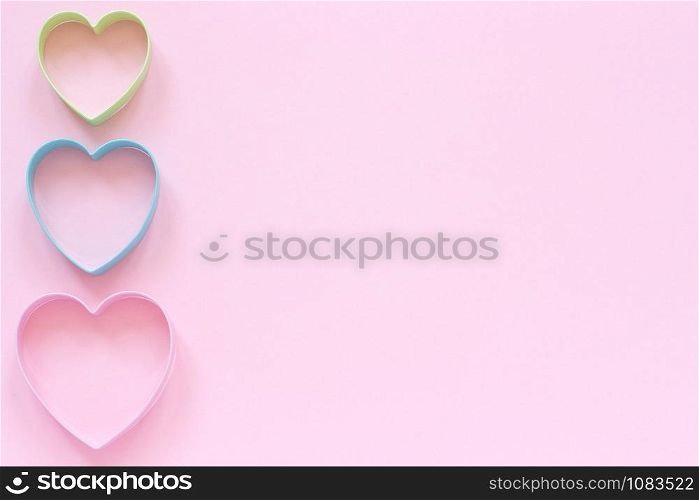 Colorful cutters cookies in heart shape on pastel pink background. Concept Valentine&rsquo;s card. Top view Copy space for text.. Colorful cutters cookies in heart shape on pastel pink background. Concept Valentine&rsquo;s card. Top view Copy space for text