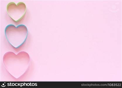 Colorful cutters cookies in heart shape on pastel pink background. Concept Valentine&rsquo;s card. Top view Copy space for text.. Colorful cutters cookies in heart shape on pastel pink background. Concept Valentine&rsquo;s card. Top view Copy space for text