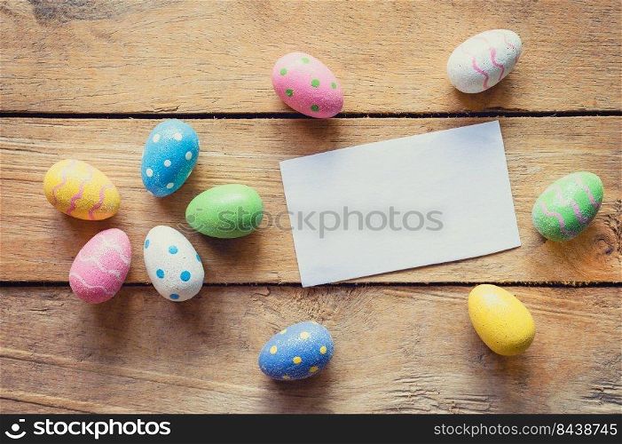 Colorful easter egg and paper card on wood background with space.