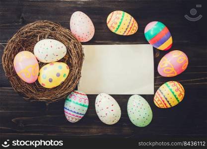 Colorful easter egg and paper on wood background with space.