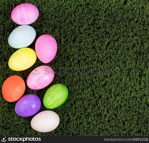 Colorful Easter egg decorations forming left hand border on green grass.