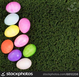 Colorful Easter egg decorations forming left hand border on green grass.