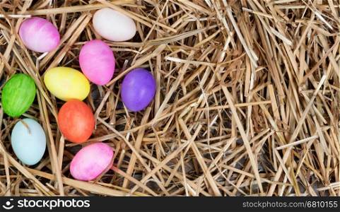 Colorful Easter egg decorations forming left hand border on natural straw and wood.