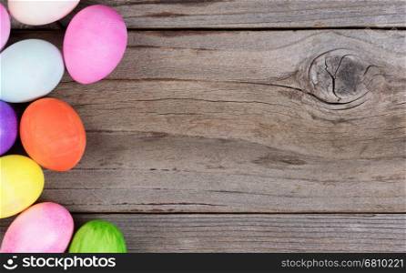 Colorful Easter egg decorations forming left hand border on rustic wood.