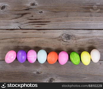 Colorful Easter egg decorations forming lower border on rustic wood.