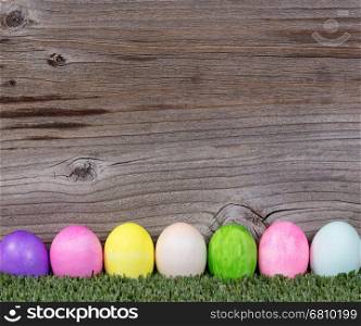 Colorful Easter egg decorations on grass with rustic wood in background.