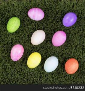 Colorful Easter egg decorations on green grass. Flat view.